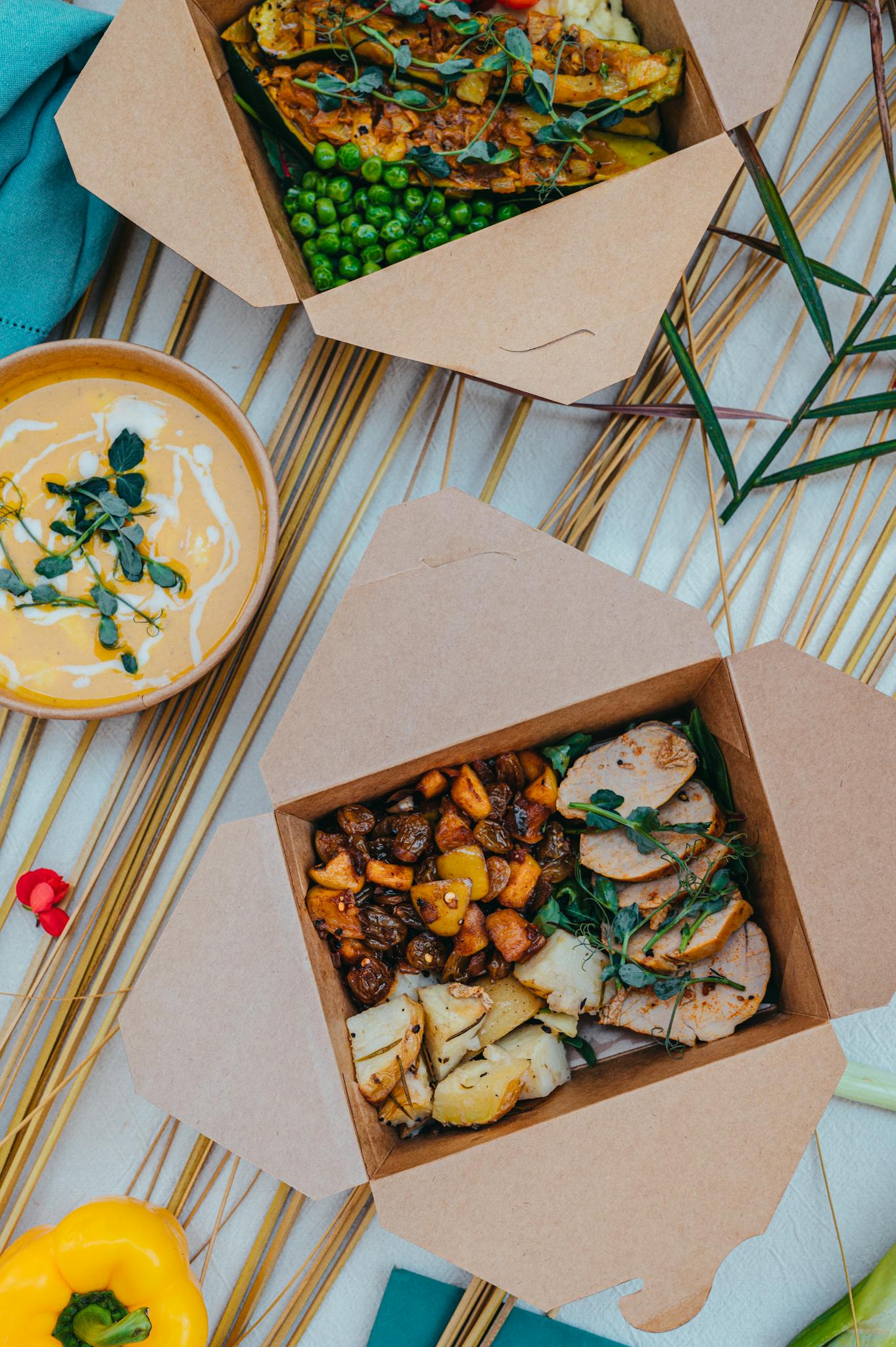 A delicious takeout meal featuring gourmet ingredients like roasted vegetables, meat, and creamy soup.