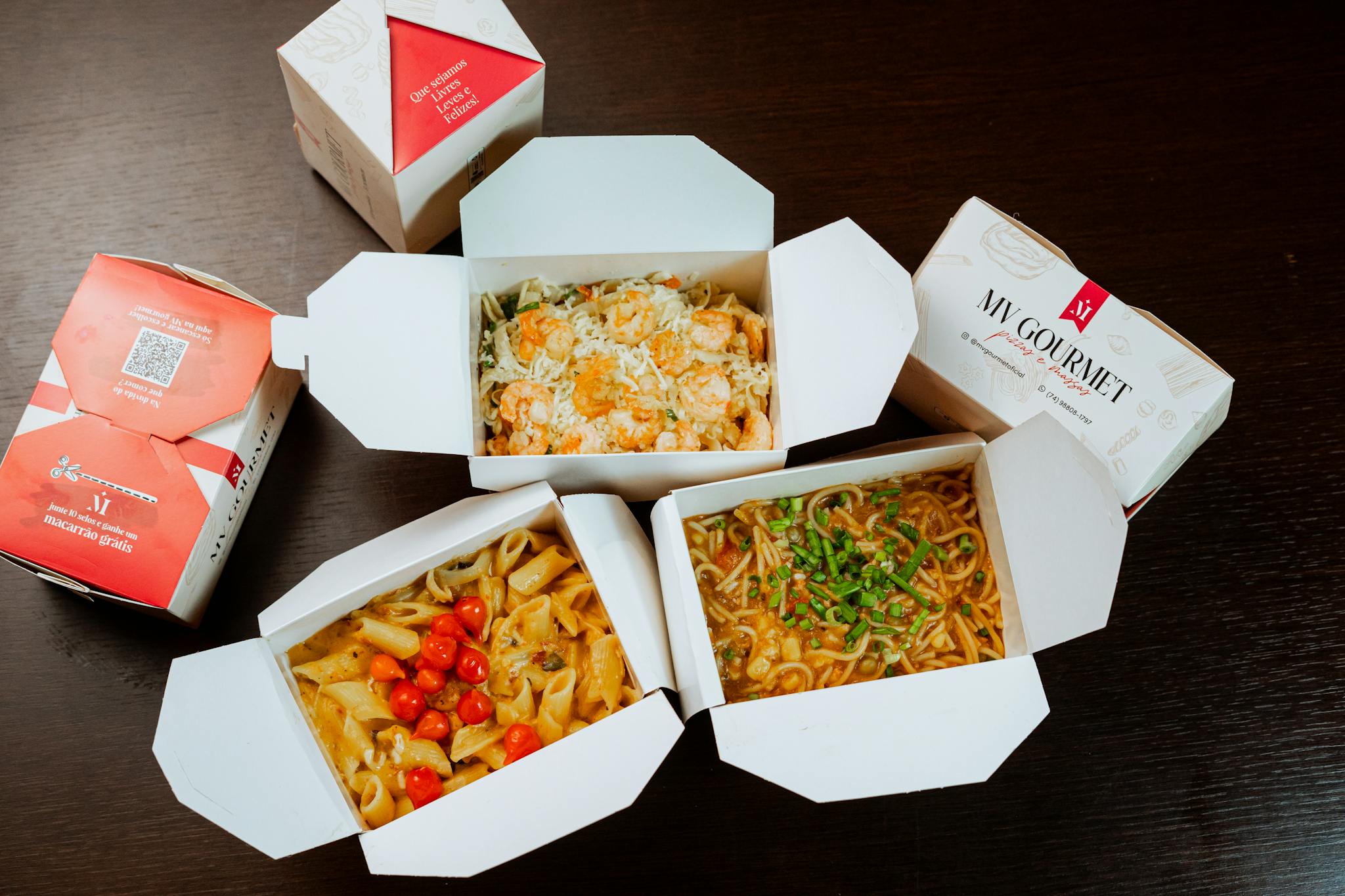 Three gourmet takeout meals in open boxes showcasing pasta and noodles.